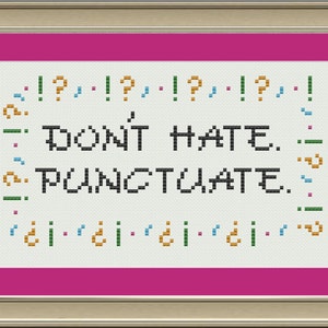 Può includere: Un ricamo a punto croce bianco con una cornice rosa. Il ricamo dice "DON'T HATE. PUNCTUATE." in testo nero con segni di punteggiatura colorati intorno al testo.