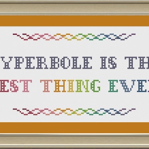 Puede incluir: Bordado de punto de cruz enmarcado en un marco dorado y plateado. El bordado dice "La hipérbole es lo mejor de todo" en un arcoíris de colores.