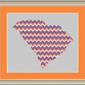 May include: A purple and orange chevron pattern in the shape of the state of South Carolina. The pattern is framed in a light orange border.