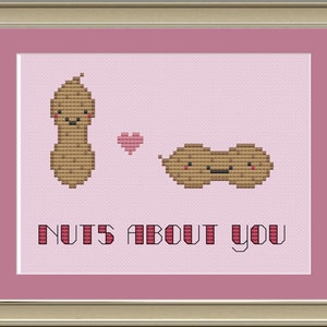 May include: A cross-stitch design featuring two cartoon peanuts with smiling faces. The peanuts are in a heart shape and the text "NUTS ABOUT YOU" is below them.