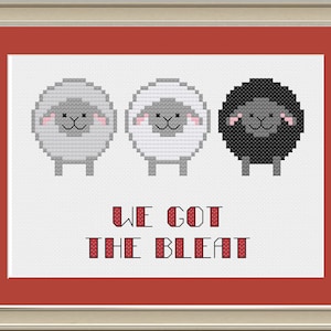 Könnte beinhalten: Gerahmtes Kreuzstich-Kunstwerk mit drei Schafen: grau, weiß und schwarz. Der Text "WE GOT THE BLEAT" ist unter den Schafen gestickt. Das Kunstwerk ist mit einem roten Passepartout und einem silberfarbenen Rahmen gerahmt.