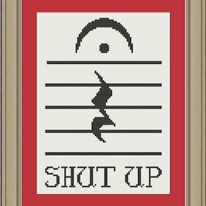 以下が含まれることがあります： 白と黒のクロスステッチのデザインで、トレブルクレフと「SHUT UP」の文字が白い背景に描かれています。デザインは赤と金のフレームで囲まれています。