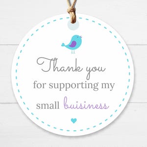 Pu&ograve; includere: Un tag rotondo bianco con un bordo a pois turchese e uno spago marrone. Il tag presenta un'illustrazione di un uccello turchese e il testo "Thank you for supporting my small business" in grigio e viola.