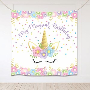 May include: A white backdrop featuring a unicorn head illustration. The unicorn has a gold horn, closed eyes, and a flower crown. The background is decorated with colourful flowers and confetti. The text "My Magical Birthday" is written in purple letters.