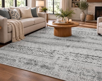 May include: A rectangular area rug featuring a light gray base with dark gray distressed horizontal bands. The pattern consists of repeating geometric shapes, including diamonds, chevrons, and linear motifs, creating a textured appearance across the surface.