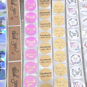 Könnte beinhalten: Eine Auswahl an Aufklebern mit Text und Designs. Rechteckige Aufkleber mit "thank you" in Schriftform und holografischem Hintergrund. Runde Aufkleber in Pink, Gold und Weiß mit Sätzen wie "handmade with love".