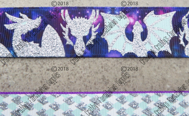 May include: Two different ribbon designs featuring a silver glitter dragon silhouette on a purple and blue galaxy background. The second ribbon is a white and light blue checkered pattern with silver glitter accents.