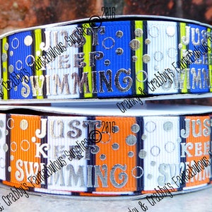 May include: Two spools of ribbon with a white, black, blue, and orange striped pattern. The ribbon has the words "Just Keep Swimming" printed in silver on it. The ribbon is 2016.