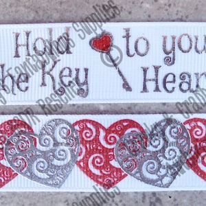 May include: White ribbon with silver and red hearts and the text "I Hold the Key to your Heart".