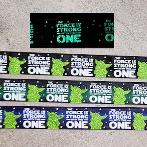May include: Black and green ribbon with a repeating pattern of a green Yoda silhouette, stars, and the text "The Force is Strong with this One".