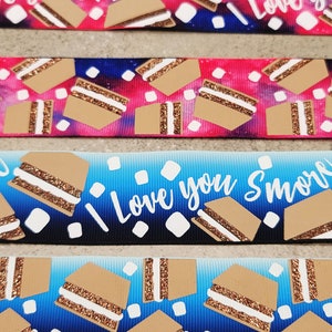 May include: A blue and pink ribbon with a white background and a pattern of s'mores and the text "Love you Smore".