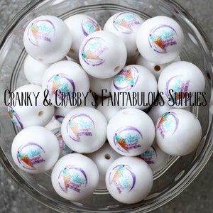 May include: A bowl of white round beads with a purple and teal design featuring the text "Ice Cream Solves Everything".