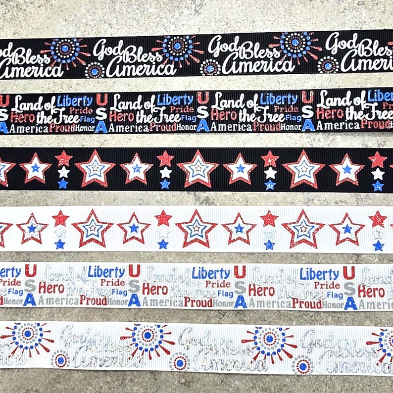 May include: Ribbons with patriotic designs. The ribbons feature text that reads "God Bless America", "Land of Liberty", and "Hero the Free". The ribbons are in red, white, and blue colors, with star and burst patterns.