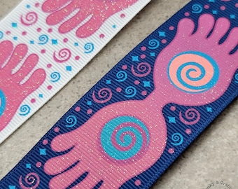 May include: Two pink glitter hands with blue and pink swirls on a navy blue ribbon. The ribbon is decorated with white and blue swirls.