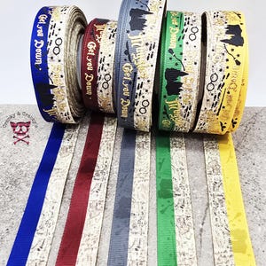 May include: A collection of decorative ribbons in various colors, including blue, burgundy, gray, green, and yellow. Each ribbon features a repeating pattern with text and graphic elements. The text "Get You Down" is visible on the blue ribbon.