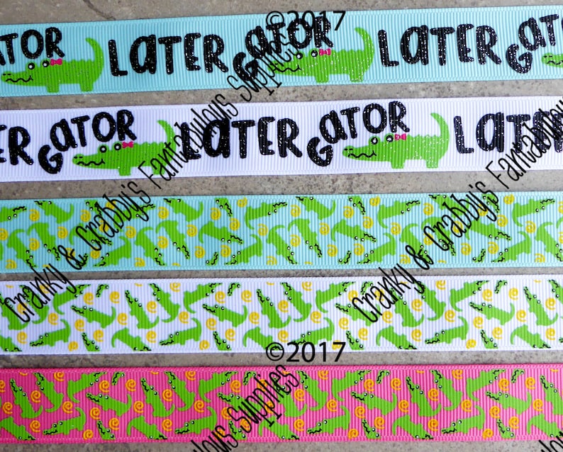 May include: Five different ribbon designs featuring a green alligator with the text "Later Gator" in black. The ribbons are in various colors, including blue, white, and pink. The ribbons are printed with a repeating pattern of alligators and yellow circles.
