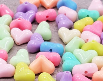 May include: A collection of pastel-colored heart-shaped plastic beads. The beads are in shades of pink, purple, blue, green, and yellow.