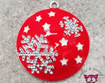 May include: Red Christmas ornament with a silver snowflake and white stars. The ornament has a silver loop for hanging.