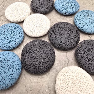 May include: An assortment of porous, round stones in various colors, including white, gray, and light blue. The stones have a textured surface with numerous small holes. The arrangement is scattered, with the stones overlapping slightly.