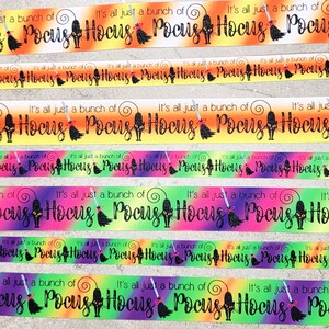 Könnte beinhalten: Nahaufnahme eines bunten Bandes mit dem Text "It's all just a bunch of Hocus Pocus", der sich über das gesamte Band wiederholt. Das Band hat einen Regenbogen-Ombre-Effekt mit schwarzen Silhouetten von Katzen und Hexen.