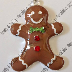 May include: A gingerbread man charm with a white icing outline and red and green rhinestones. The charm is made of metal and has a silver finish.