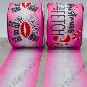Puede incluir: Dos carretes de cinta rosa y blanca con un diseño degradado. Un carrete presenta el texto "Christmas is SO Fetch" con corazones rojos y bastones de caramelo. El otro carrete presenta el texto "Book It" con un labio rojo y cuadrados negros.
