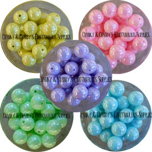 May include: Four bowls of iridescent, round, plastic beads in four different colors: yellow, lavender, green, and blue.  The bowls are white with a black text label that reads "CRANKY & CRABBY'S FANTABULOUS SUPPLIES".