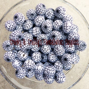 May include: A bowl filled with white and black round beads. The beads have a spiderweb design.