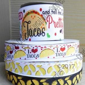 May include: A stack of four white and black ribbon rolls with a taco theme. The top ribbon has the text "and tell me I'm pretty tacos" printed on it. The second ribbon has the text "I love tacos" printed on it. The third ribbon has a pattern of yellow tacos on a white background. The bottom ribbon has a pattern of yellow tacos on a black background.