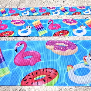 May include: Three ribbons with a summer pool theme. The ribbons feature a blue water background with pink flamingos, donut pool floats, unicorn pool floats, and colorful inflatable rafts. The ribbons are made of a textured material.