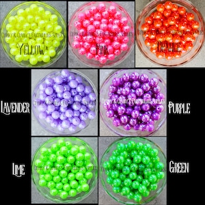 May include: Assortment of iridescent beads in various colors, including yellow, pink, orange, lavender, purple, lime, and green. The beads are displayed in clear bowls.