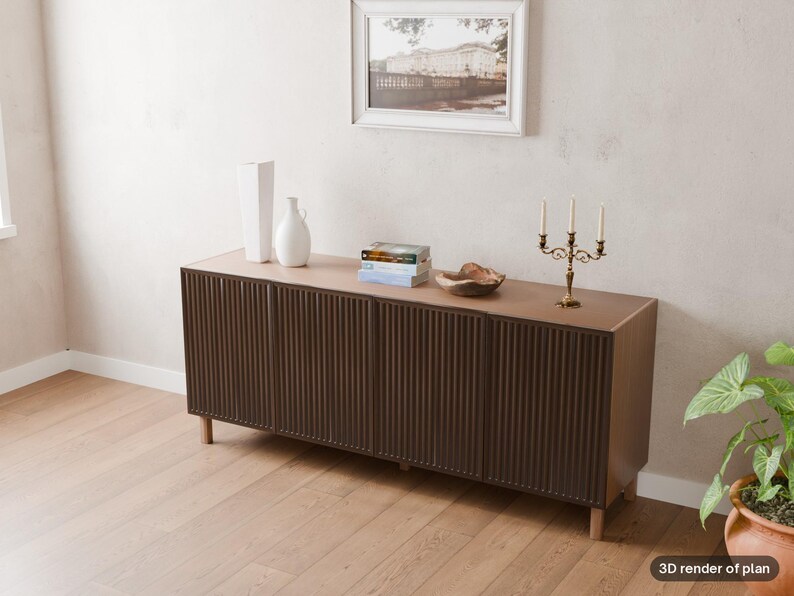 May include: A long, dark brown wooden sideboard featuring four cabinet doors with a vertical ribbed texture. The sideboard stands on light-coloured wooden legs and is topped with two white vases, a stack of books, a wooden bowl, and a gold candelabra.