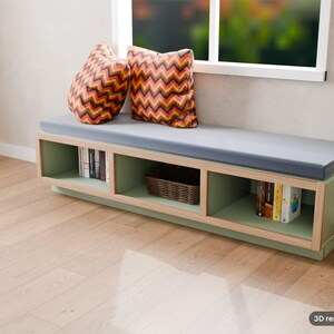 May include: A low, rectangular sage green storage bench with a light wood frame and a gray cushioned seat. Two square pillows with a red, orange, and black chevron pattern sit on top. The base features three open cubbies containing books and a basket.