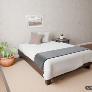 May include: A low-profile dark wood bed frame with a white mattress, a gray runner, and two square pillows in beige and white. A small potted plant sits on a dark wood side table, and a framed picture hangs on the wall above the bed.
