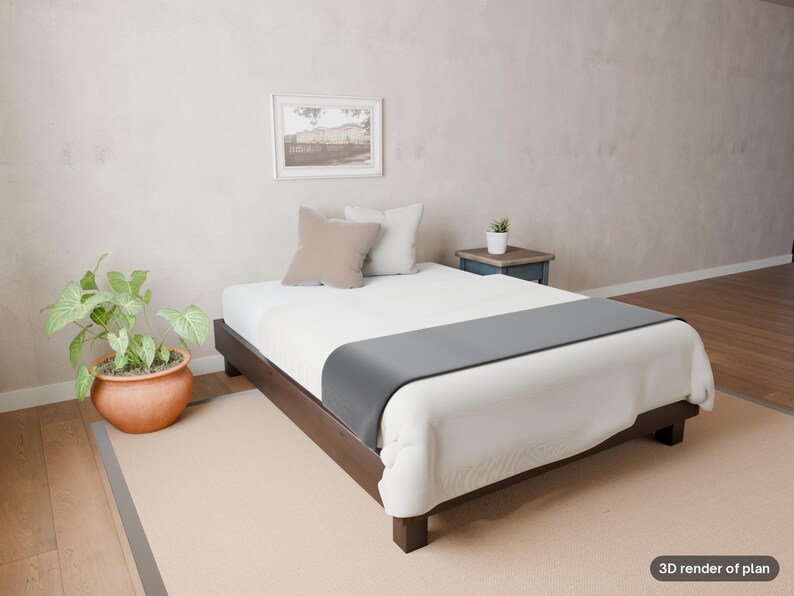 May include: A low-profile dark wood bed frame with a white mattress, a gray runner, and two square pillows in beige and white. A small potted plant sits on a dark wood side table, and a framed picture hangs on the wall above the bed.