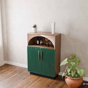 May include: A wooden cabinet featuring a light brown frame, two dark green fluted doors with vertical gold handles, and an open arched upper shelf containing two wine bottles and two gold-rimmed glasses. The text 3D render of plan is visible.
