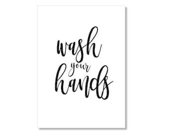 May include: Black and white printable sign with the text "wash your hands" in a cursive font.