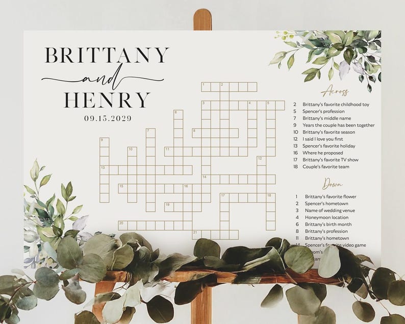 May include: A wedding crossword puzzle sign featuring the names "Brittany and Henry" and the date "09.15.2029". The sign includes a crossword grid with clues related to the couple, adorned with floral and greenery accents.