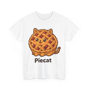 Puede incluir: Una camiseta blanca con un gráfico de un gato marrón con forma de tarta de cerezas con corteza de rejilla. El gato tiene grandes ojos negros, mejillas rosadas y una pequeña sonrisa. Debajo de la ilustración, la palabra Piecat está impresa en marrón.