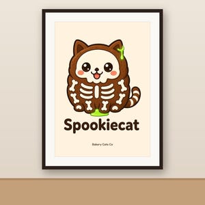 May include: A framed art print featuring a brown cartoon cat wearing a white skeleton costume with green slime accents. The text Spookiecat is printed in dark brown below the cat, with the smaller text Bakery Cats Co at the bottom.