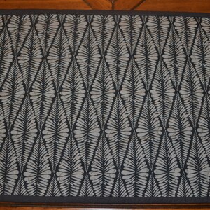 May include: Black and white patterned table runner with a geometric diamond design. The pattern features a stylized leaf design.