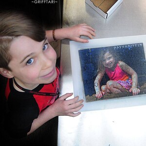 Personalized puzzle that is a gift to a sister from A young boy is looking up at the camera.  He is showing a custom puzzle of his sister.  The Missing Piece Puzzle Company