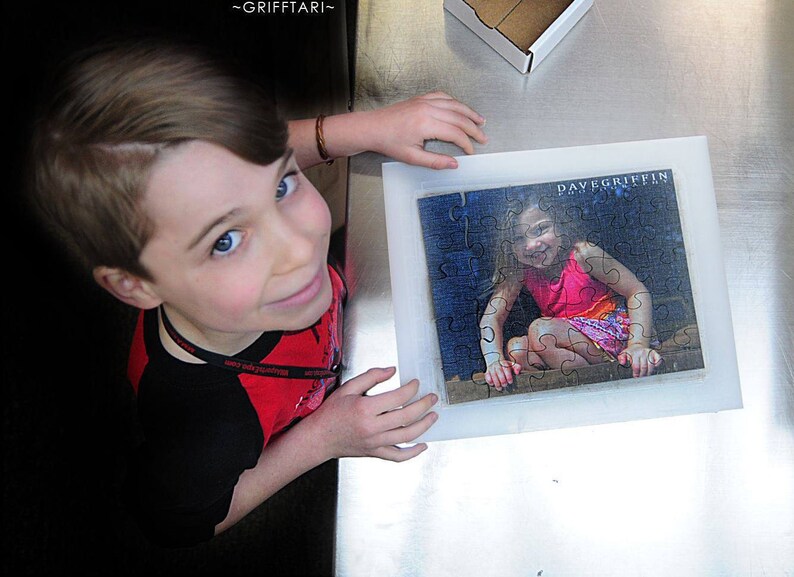 Personalized puzzle that is a gift to a sister from A young boy is looking up at the camera.  He is showing a custom puzzle of his sister.  The Missing Piece Puzzle Company