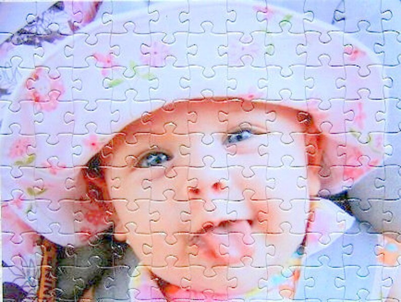 custom photo puzzle of a young baby wearing a pink hat with flowers.  Baby is sticking tongue out while smiling - The Missing Piece Puzzle Company