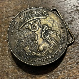 Vintage buckle Coca Cola woman with hat circular shaped advertising brass colored belt buckle