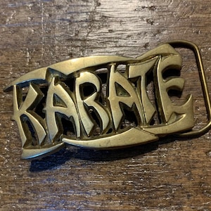 May include: A brass belt buckle with the word "KARATE" embossed in a stylized font.
