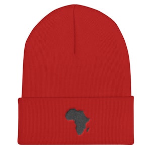 May include: Red knit beanie with a black embroidered outline of the continent of Africa.
