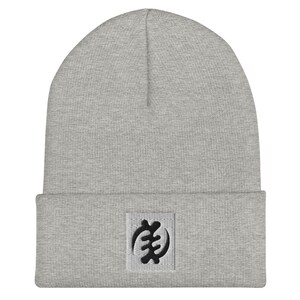 May include: Gray beanie with a black Adinkra symbol embroidered on the front.