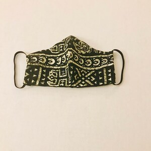 May include: Black and white patterned face mask with a geometric design. The mask has elastic ear loops.