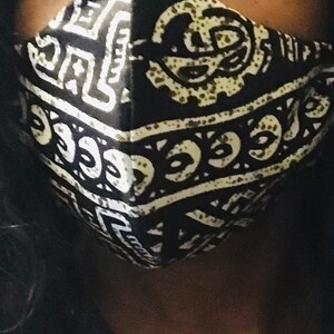 May include: Black and white face mask with a geometric pattern. The pattern features a repeating design of circles and lines.